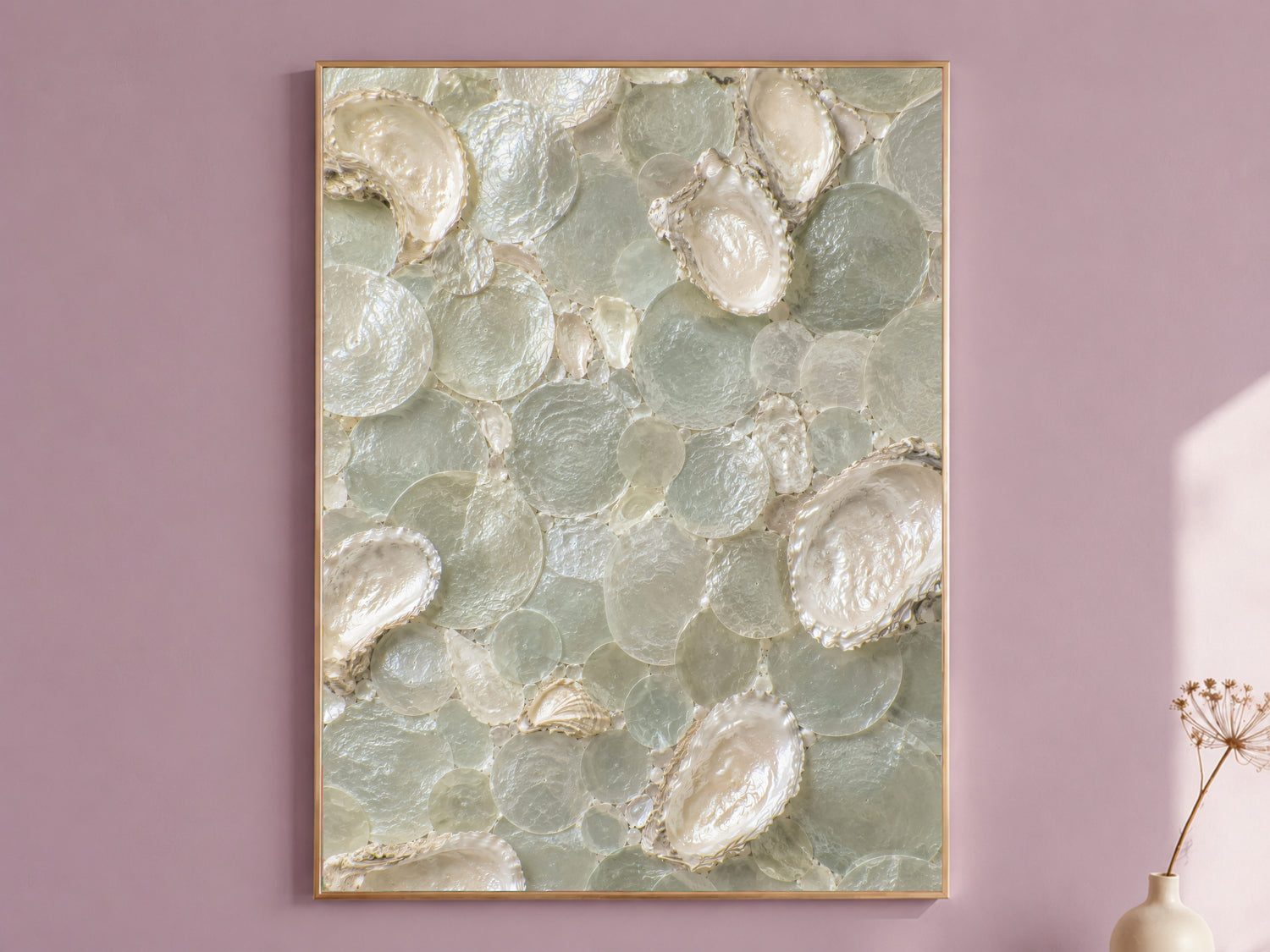 Sea glass oyster shell wall art framed in gold, displayed on a dusty mauve wall with a dried flower stem