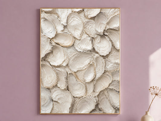 Oyster shell wall art in a thin gold frame hanging on a dusty mauve wall, styled with a small dried flower vase.