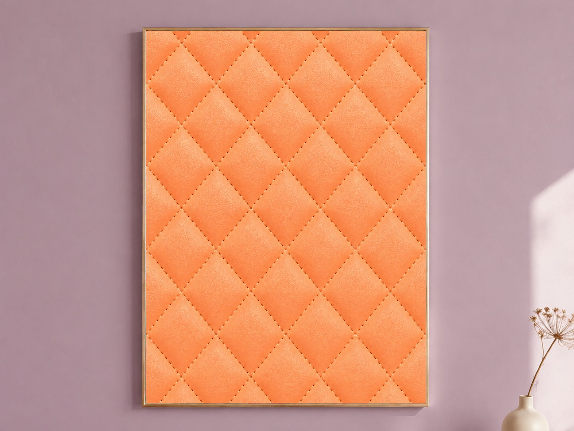 Framed quilted leather wall art in bold coral orange, styled on a dusty mauve wall