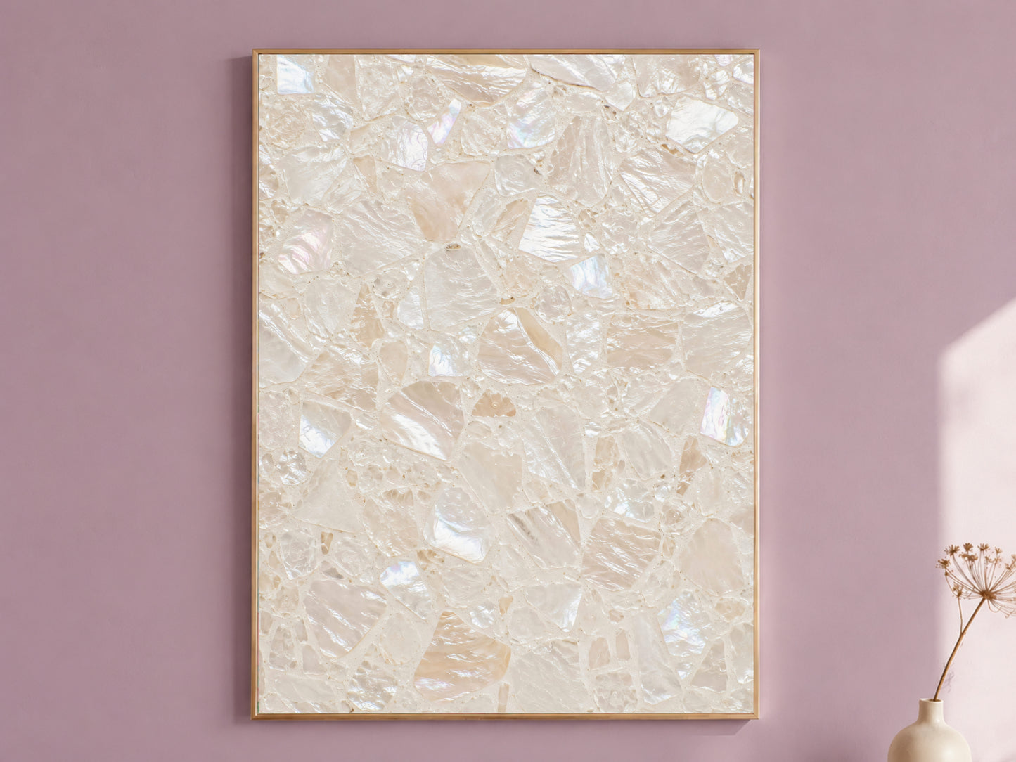 Terrazzo wall art in a thin gold frame hanging on a dusty mauve wall, styled with a small dried flower vase.