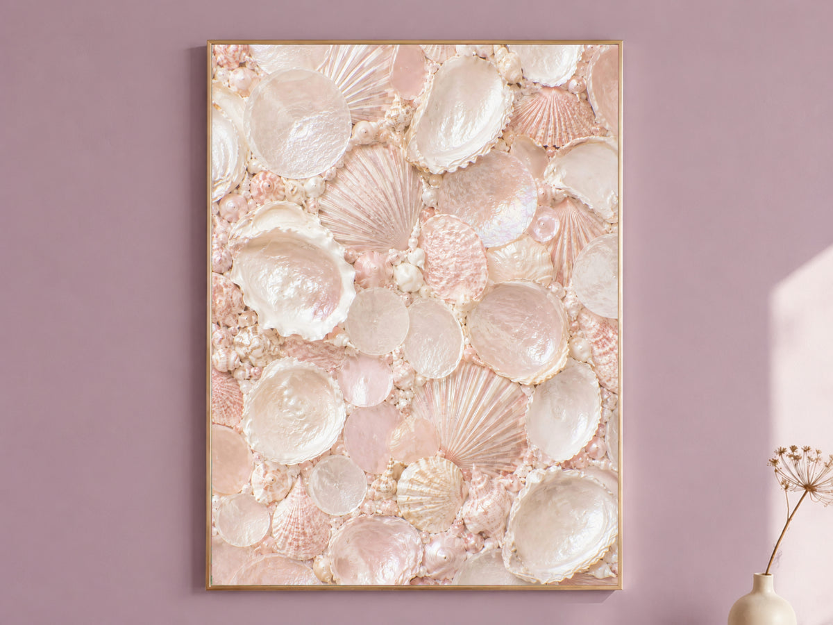 Blush pink seashell mosaic wall art framed in gold, displayed on a dusty mauve wall with a dried flower stem
