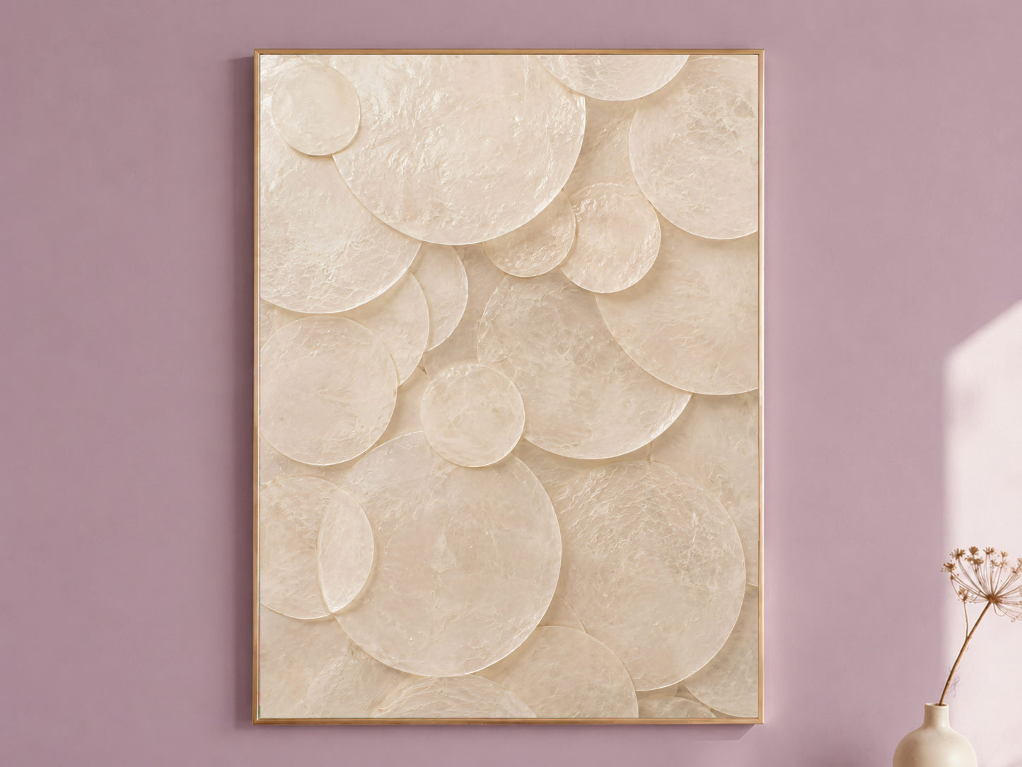 Capiz shell circle wall art framed in gold, displayed on a dusty mauve wall with a dried flower stem