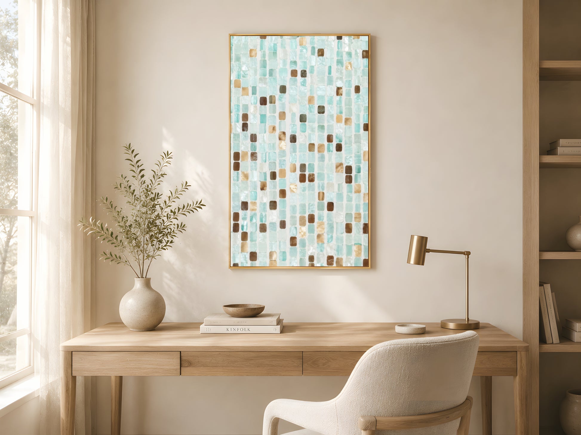 Teal mosaic tile print in gold frame above wooden desk in warm minimalist home office with cream armchair and soft natural light
