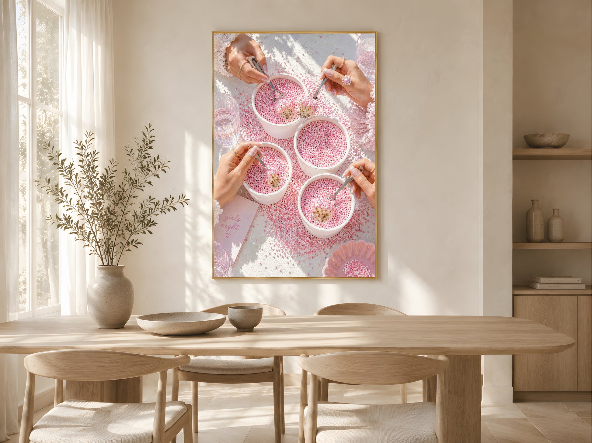 Pink coquette dot cake wall art print in a gold frame above a light oak dining table in a warm Scandinavian dining room with dried botanicals and soft natural light

