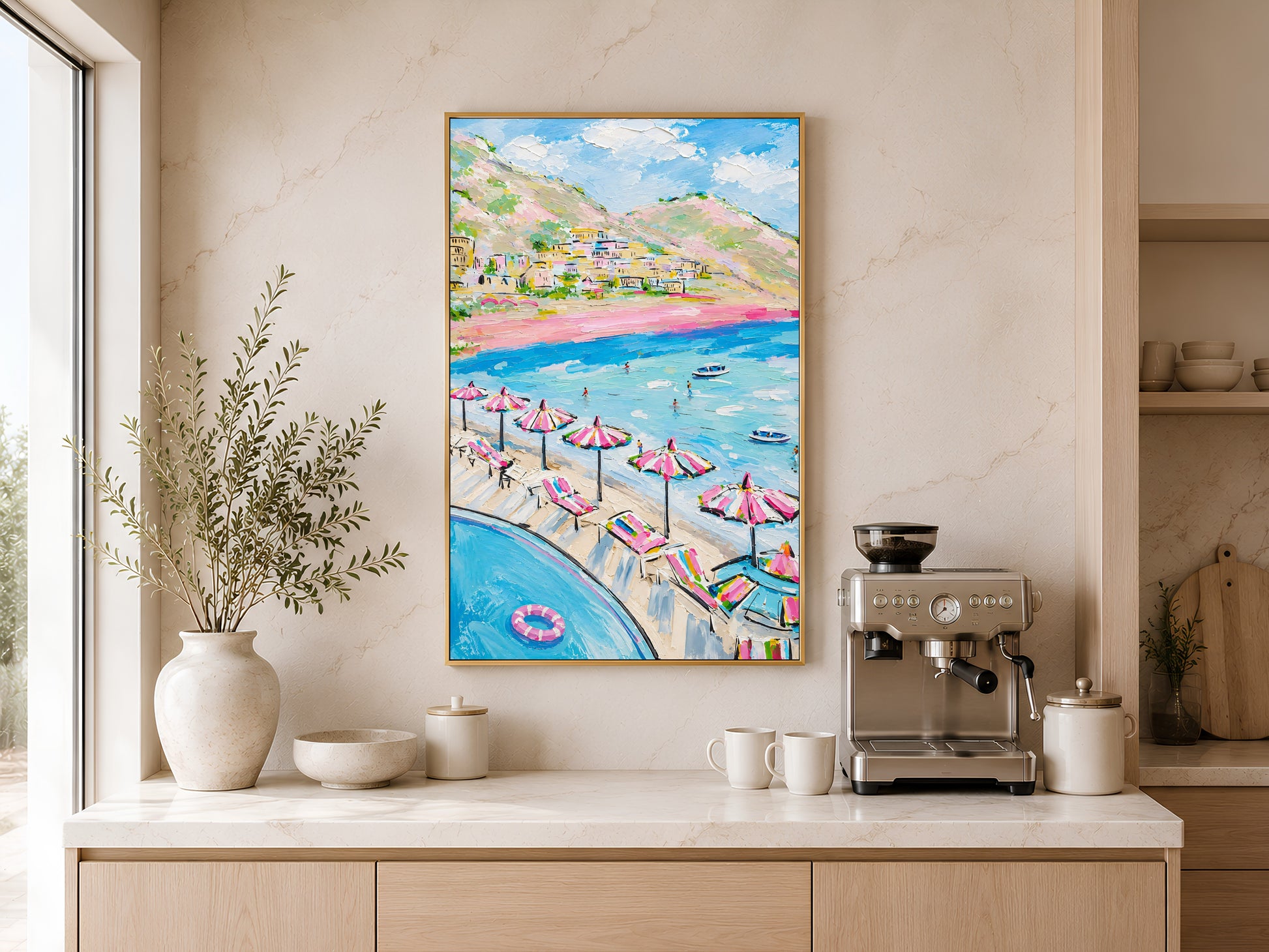 Colorful Positano beach wall art in a wood frame displayed above a coffee station in a warm minimalist kitchen with cream cabinetry and dried greenery
