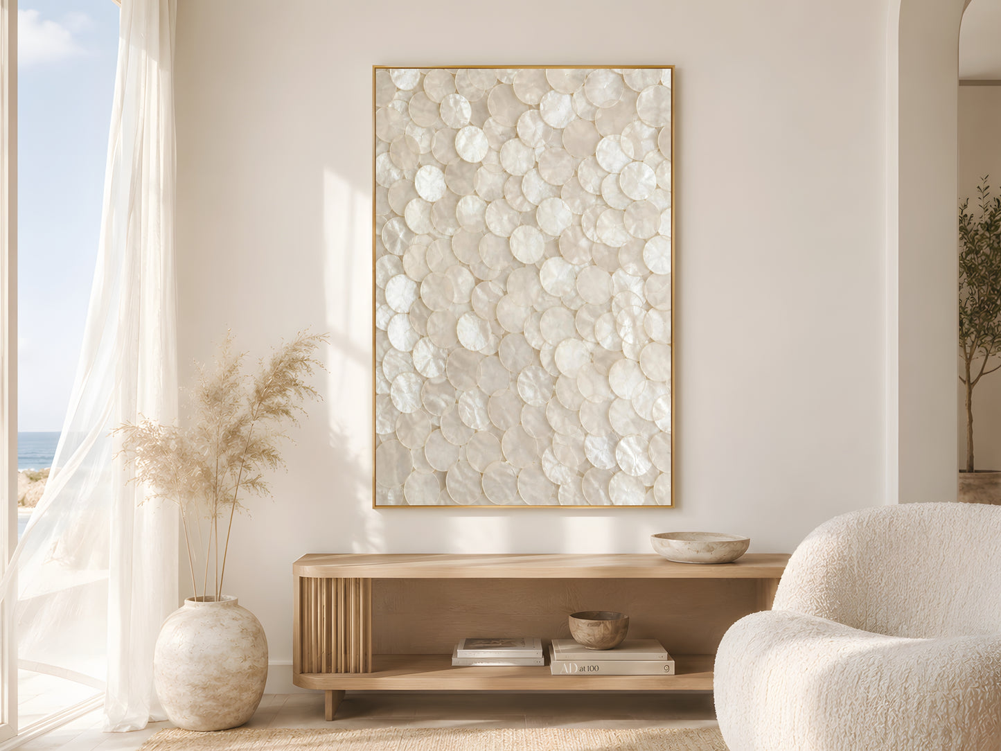 Capiz shell abstract print in gold frame beside sheer white curtains in bright minimalist living room with coastal decor and soft natural light
