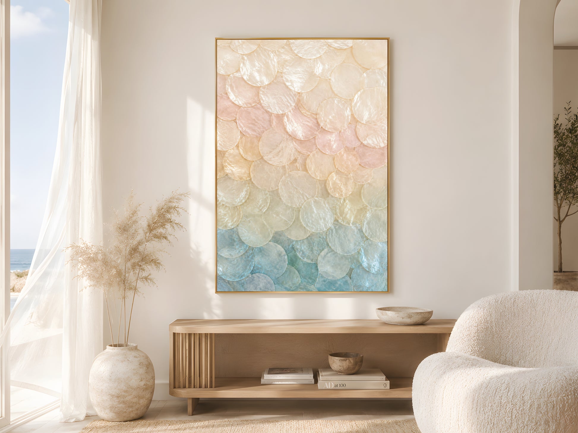 Pastel capiz shell ombré print in gold frame beside sheer curtains in bright coastal living room with cream bouclé chair and soft natural light
