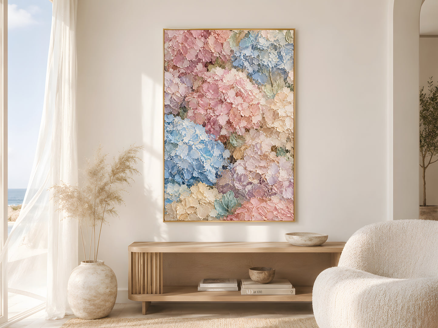Pastel hydrangea wall art print in a gold frame in a bright coastal living room with a round white chair and pampas grass
