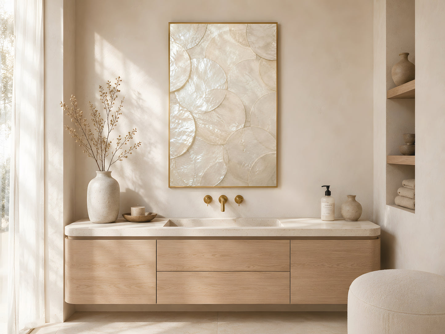 Large capiz shell pearlescent print in gold frame above wooden sideboard in warm minimalist Japandi bathroom with gold fixtures and dried botanicals
