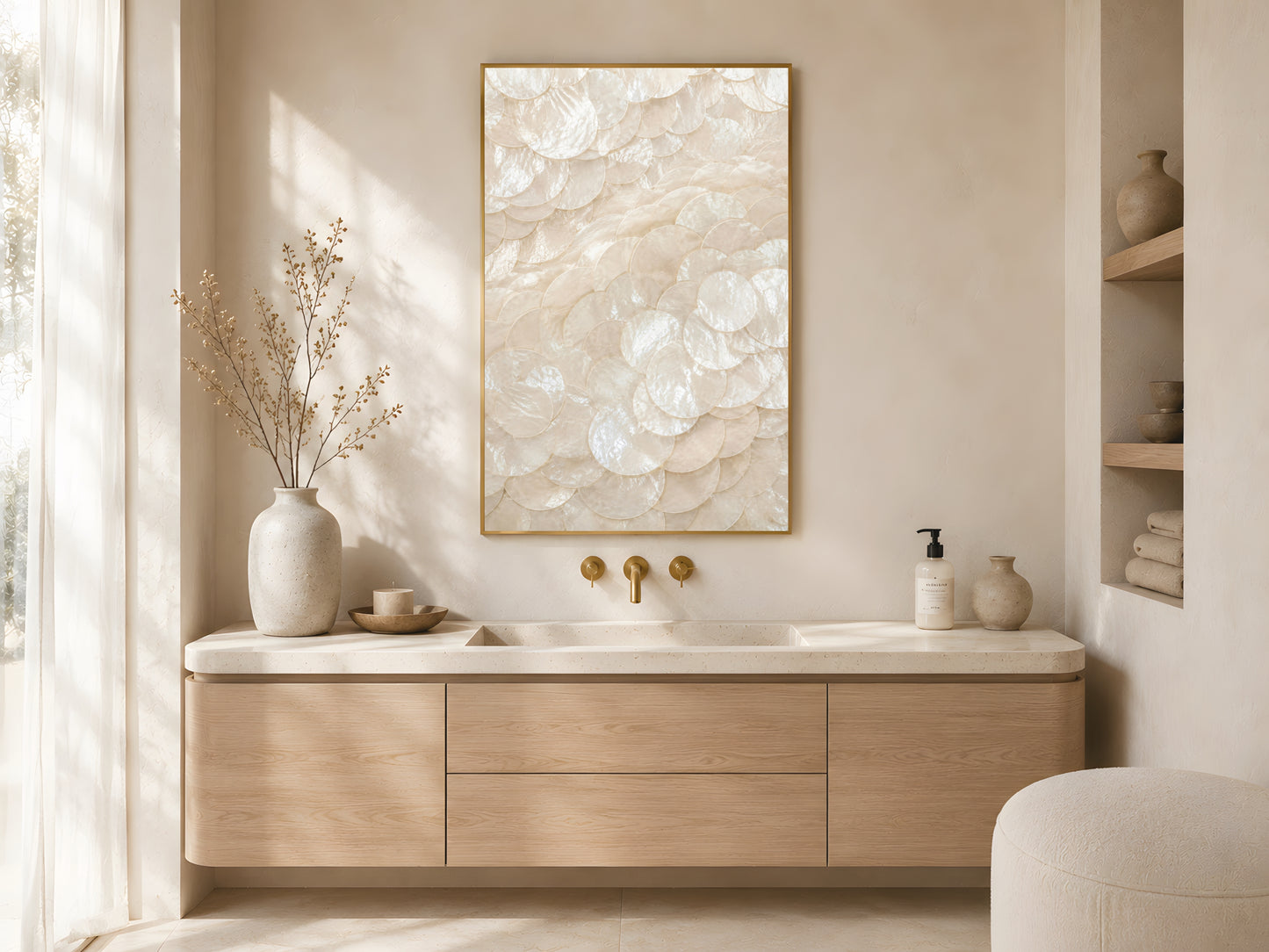 Capiz shell spiral print in gold frame above wooden sideboard in warm minimalist Japandi bathroom with gold fixtures and cream vase
