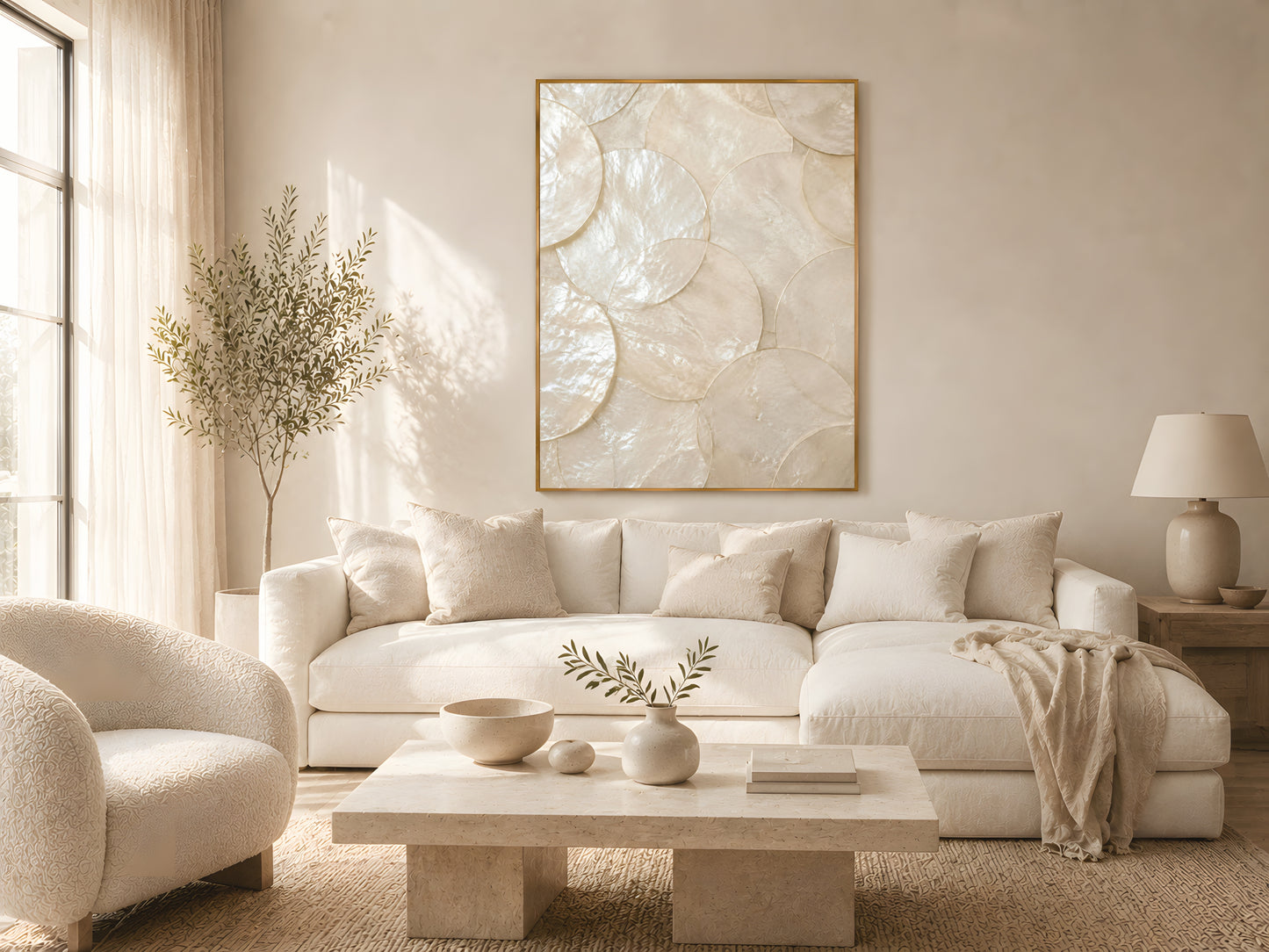 Large capiz shell pearlescent wall art in gold frame on warm white wall in bright living room with two cream sofas and natural wood furniture
