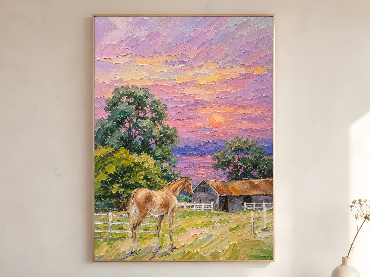 Farmhouse horse sunset impasto oil painting print in a gold frame leaning against a warm white wall with dried botanicals, showing the full painting with chestnut horse, white fencing, grey barn, green trees, and lavender pink orange sunset sky
