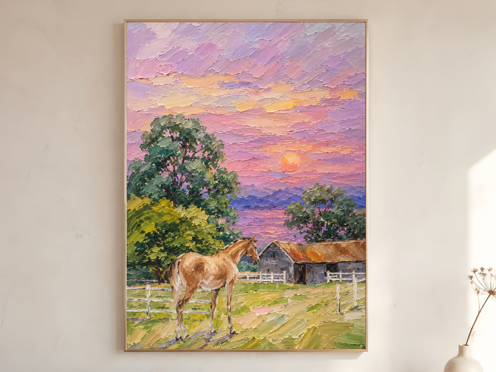 Farmhouse horse sunset impasto oil painting print in a gold frame leaning against a warm white wall with dried botanicals, showing the full painting with chestnut horse, white fencing, grey barn, green trees, and lavender pink orange sunset sky
