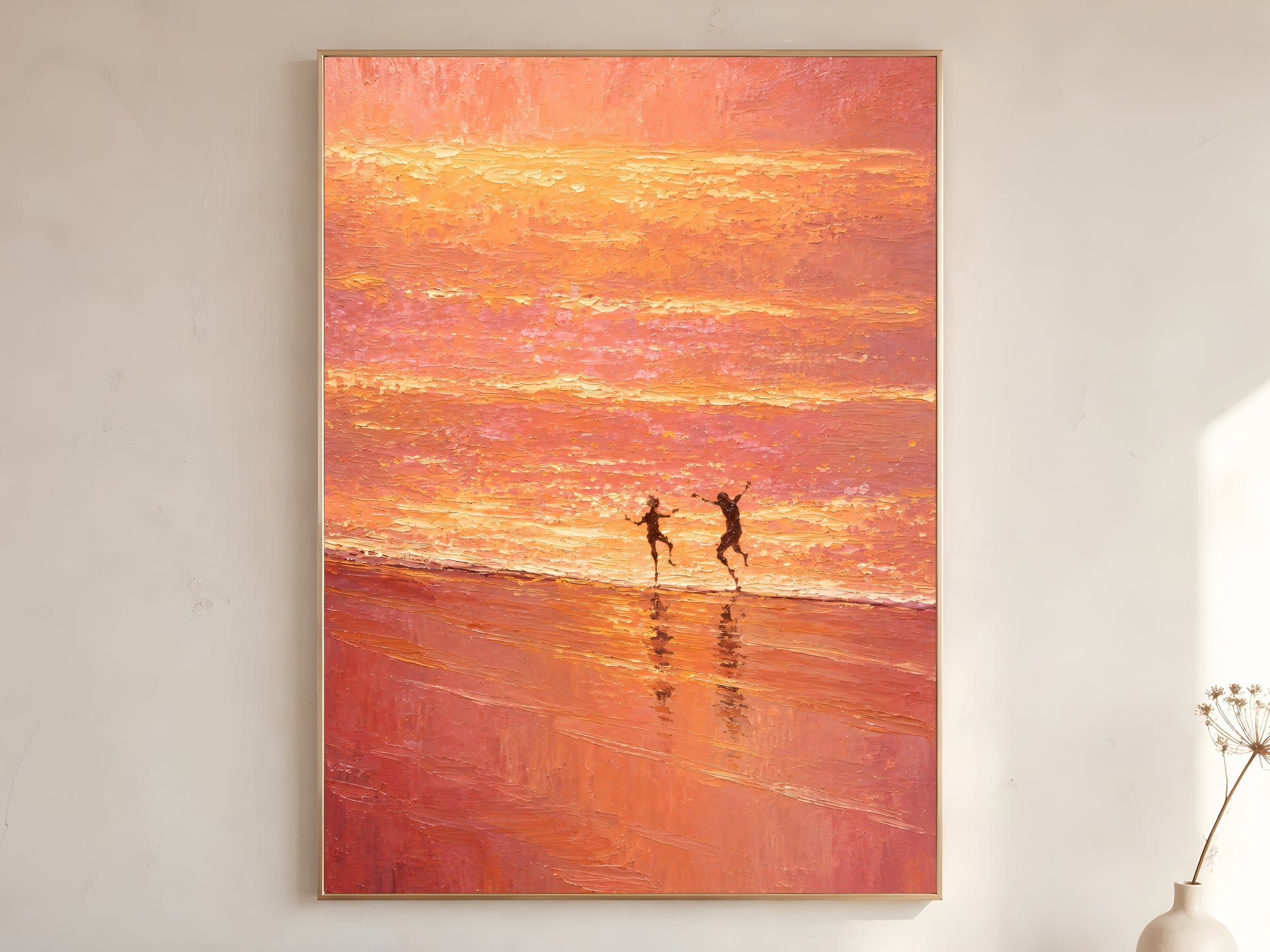 Pink sunset beach wall art printable featuring two figures running along the shoreline beneath a glowing peach and coral sunset displayed in a warm neutral interior.