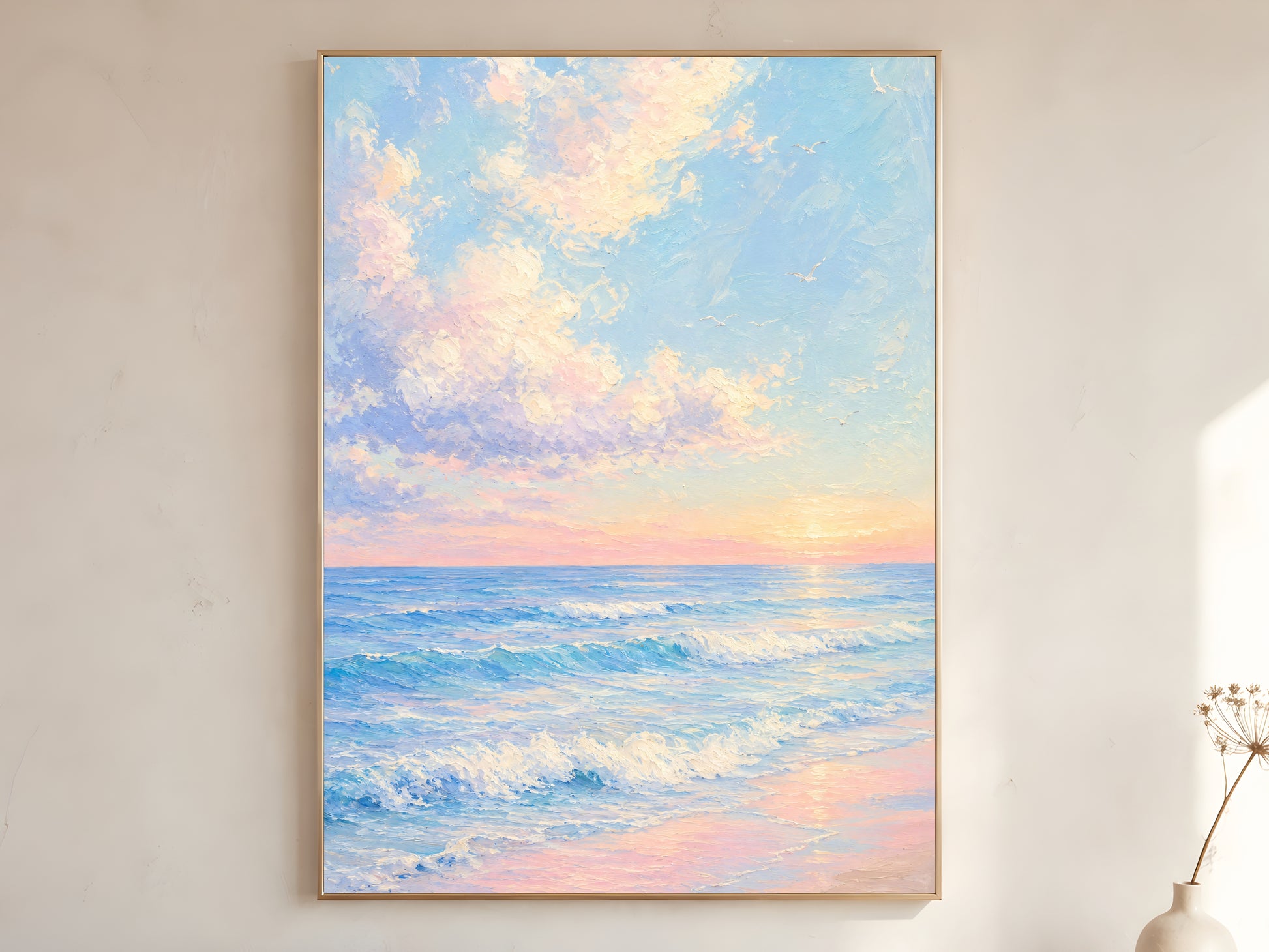 Large framed impasto pastel ocean sunrise wall art in gold frame leaning against white wall with dried botanicals in bright minimal room
