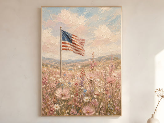 American flag wildflower field impasto oil painting print in a gold frame leaning against a warm white wall with dried botanicals, showing the full painting with pink cosmos, white daisies, rolling hills, and chalky pastel sky
