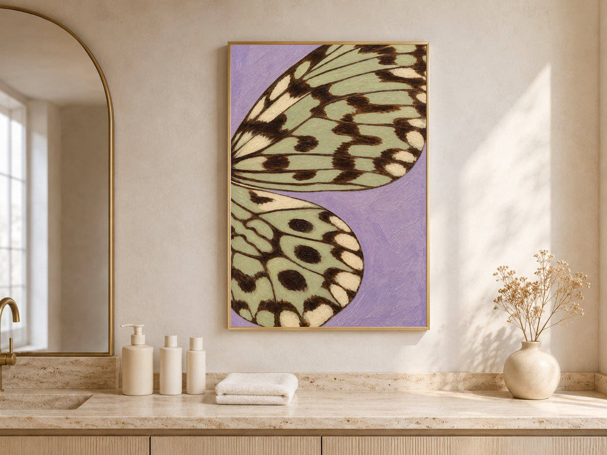 Lavender sage green butterfly wing print framed above a bathroom counter in a warm neutral bathroom