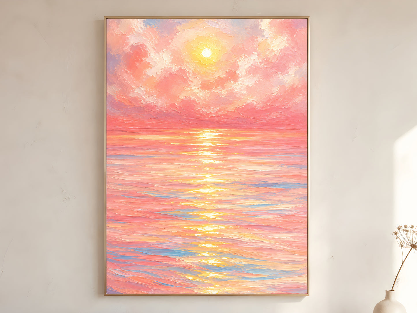 Large framed impasto pink sunset ocean wall art in gold frame leaning against white wall with dried botanicals in bright minimal room
