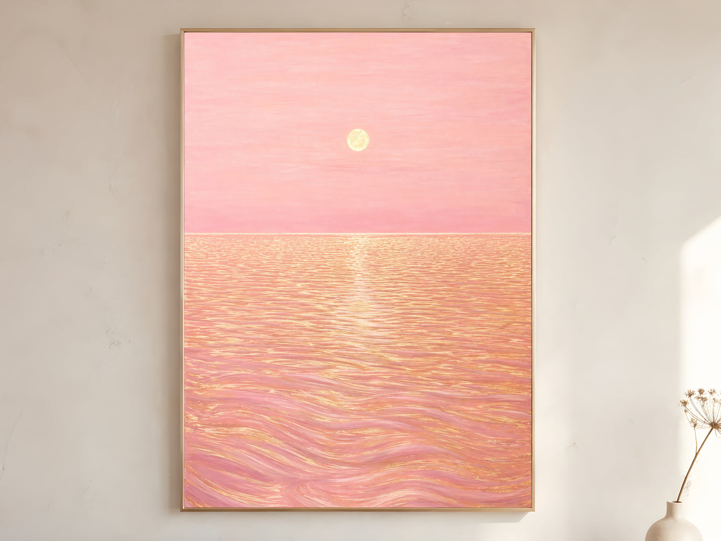 Pink sunset ocean wall art print in gold frame hanging above a console with a vase of branches
