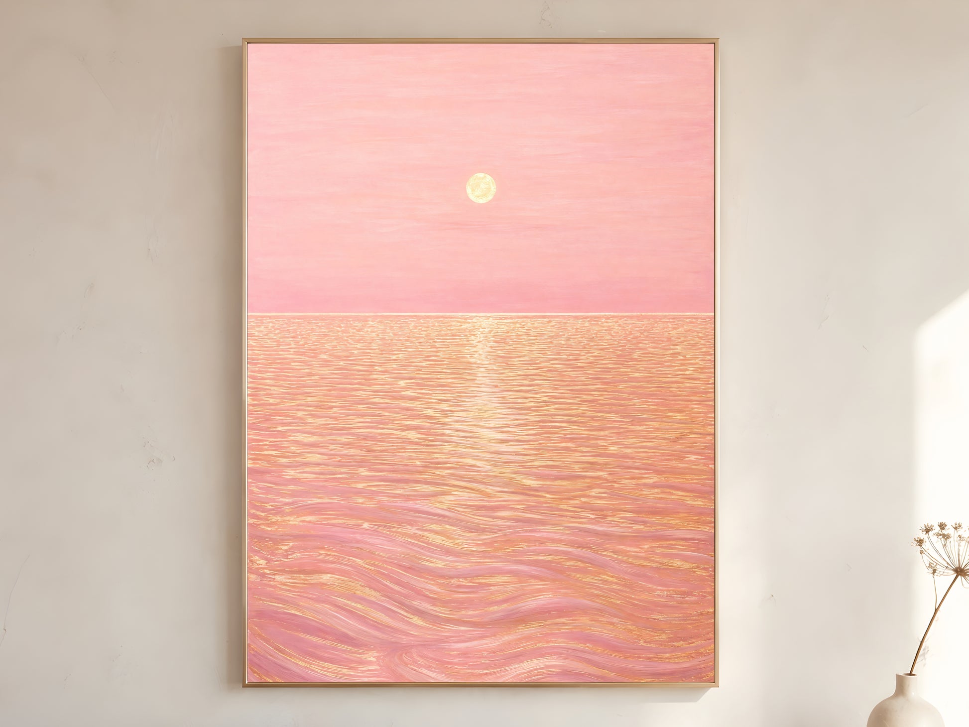 Pink sunset ocean wall art print in gold frame hanging above a console with a vase of branches
