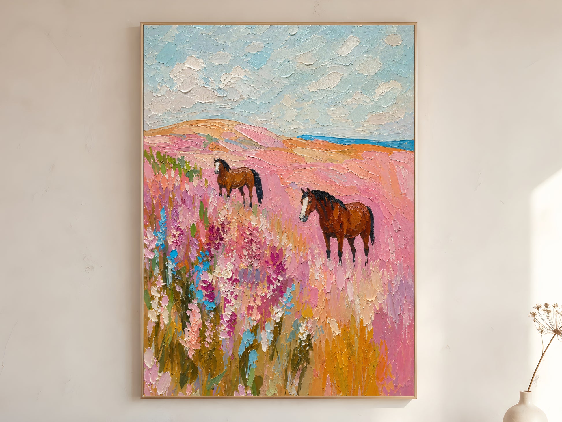 Horse in pink wildflower field impasto oil painting print in a thin natural wood frame, leaning against a warm white wall with a dried wildflower stem
