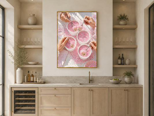 Pink coquette dot cake wall art print in a gold frame above open kitchen shelving in a warm neutral Scandinavian kitchen with wood accents and ceramics
