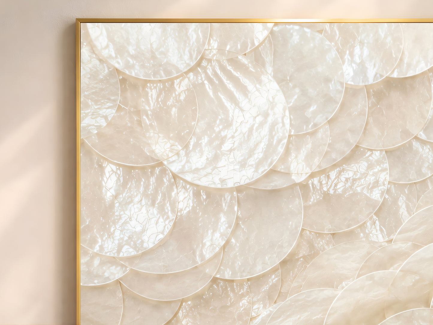 Close-up of capiz shell swirl wall art in gold frame showing dramatic spiral arrangement of overlapping pearlescent ivory and warm white shell discs catching natural light
