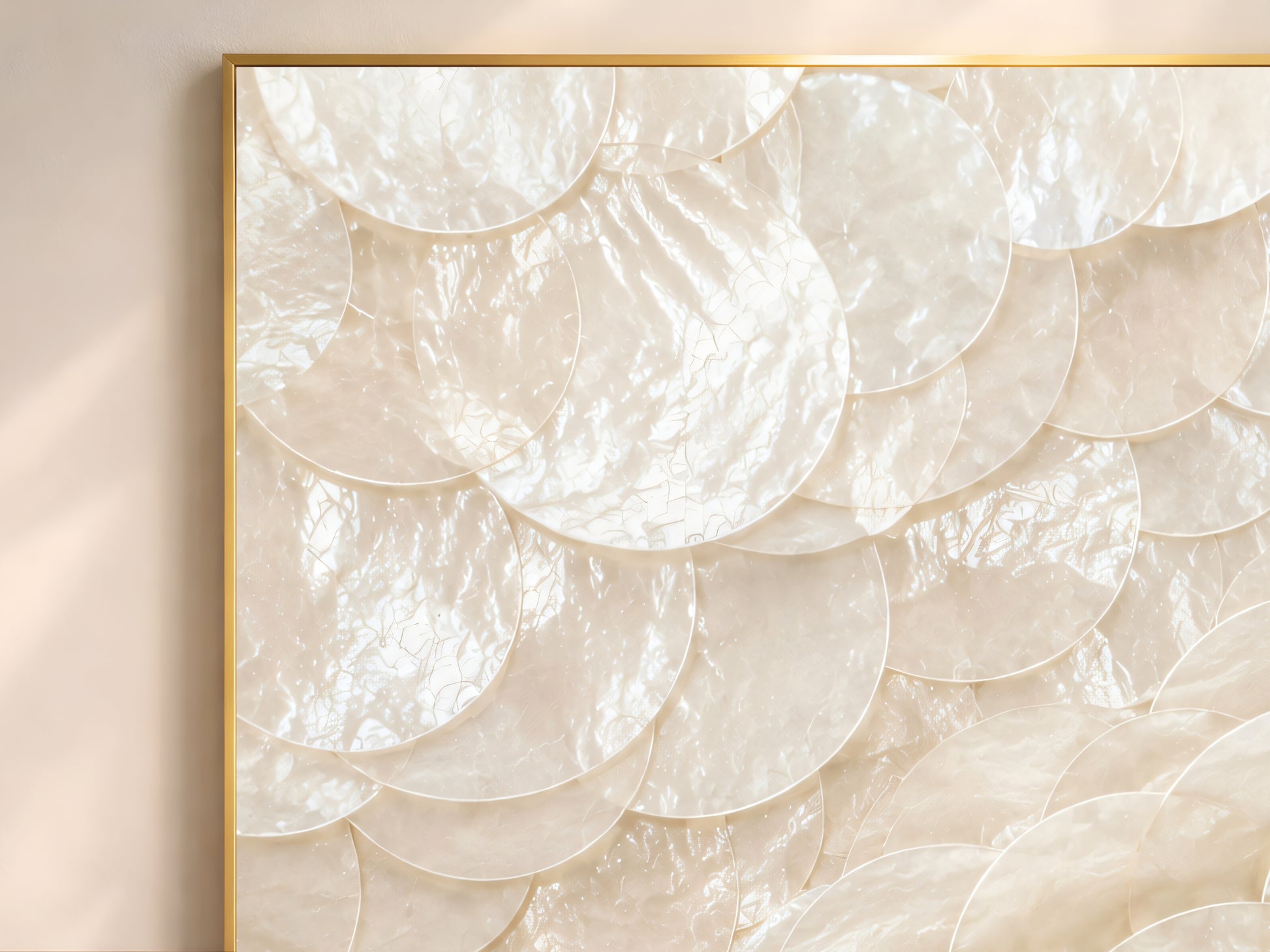 Close-up of capiz shell swirl wall art in gold frame showing dramatic spiral arrangement of overlapping pearlescent ivory and warm white shell discs catching natural light
