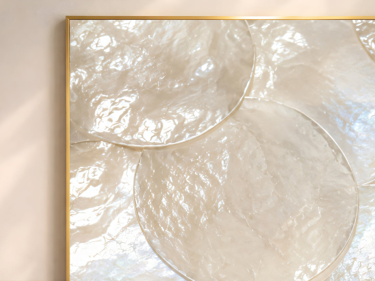 Close-up of mother of pearl iridescent shell wall art in gold frame showing large overlapping pearl white shell discs with soft violet aqua and champagne gold shimmer
