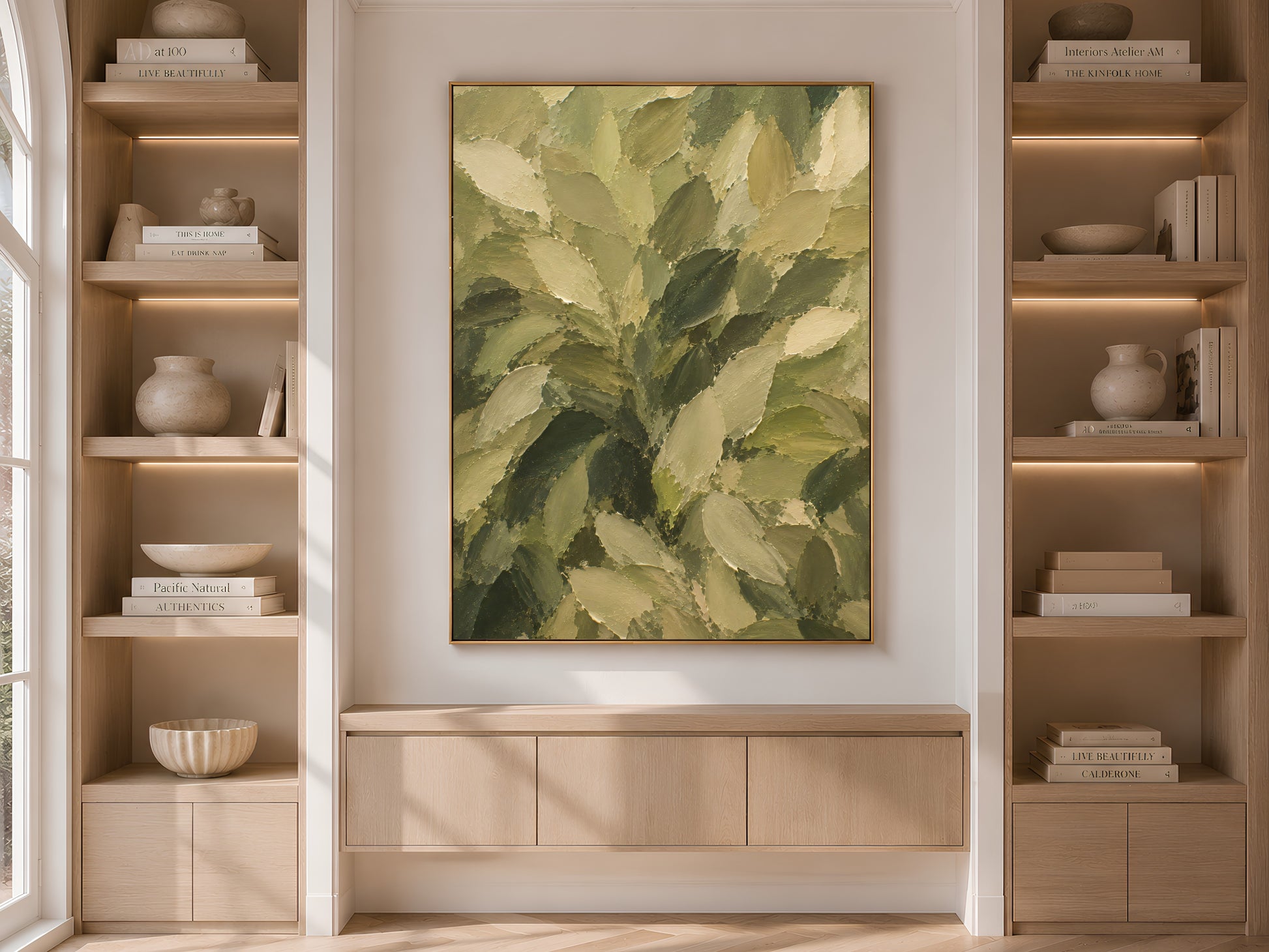 Olive green leaf wall art print displayed above a built-in cabinet between wooden bookshelves