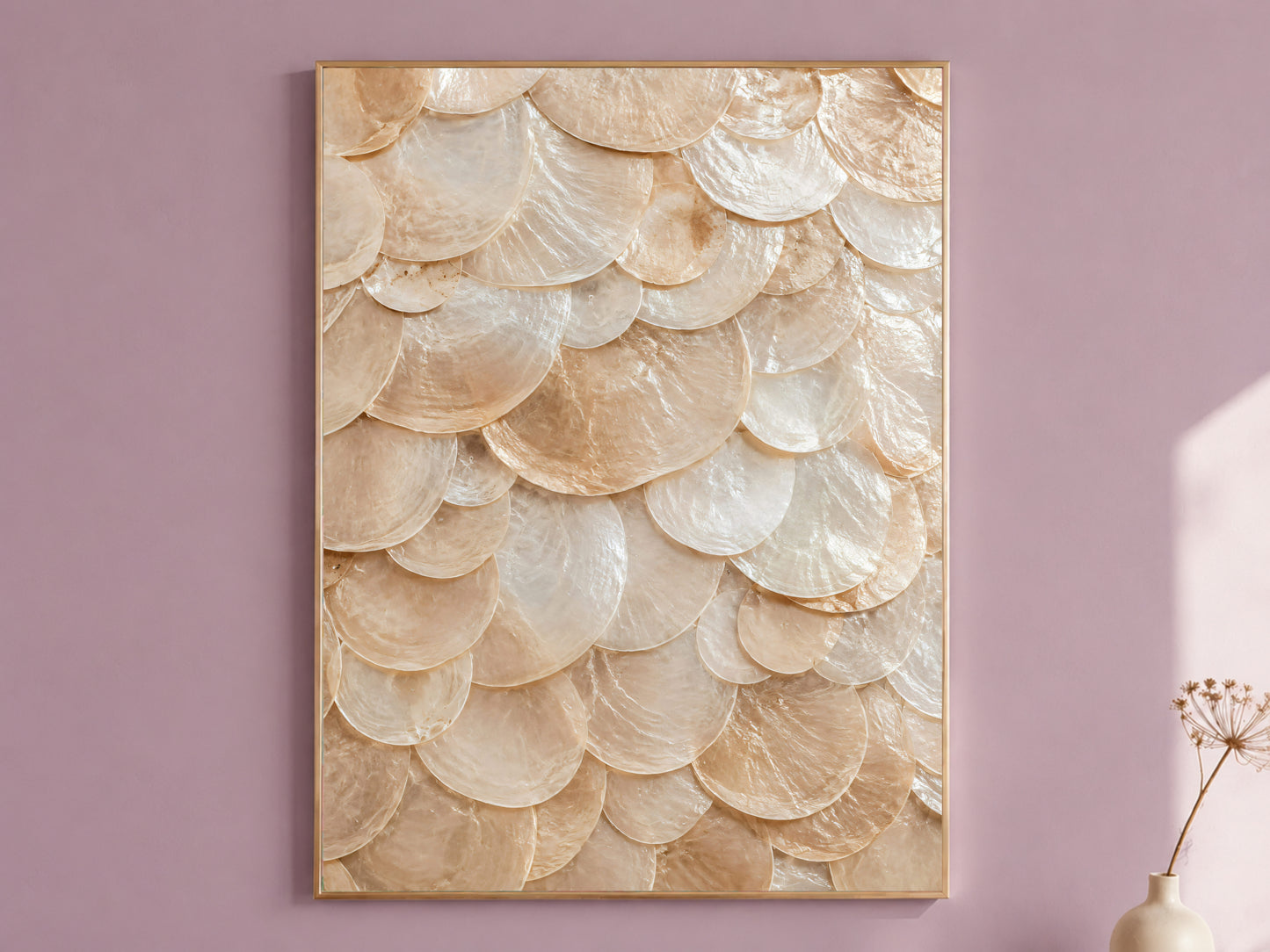 Capiz shell wall art in a thin gold frame hanging on a dusty mauve wall, styled with a small dried flower vase.