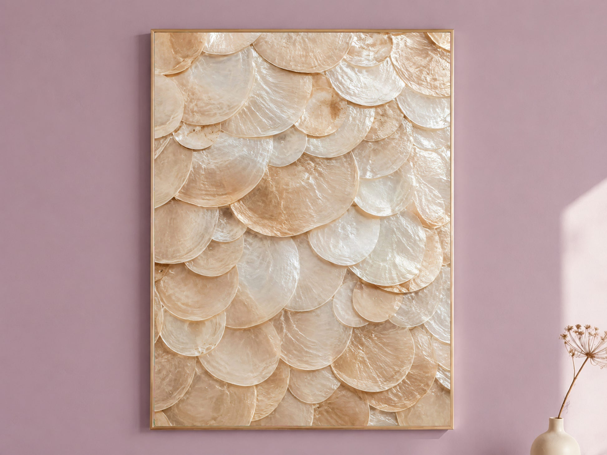 Capiz shell wall art in a thin gold frame hanging on a dusty mauve wall, styled with a small dried flower vase.