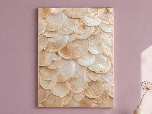 Capiz shell wall art in a thin gold frame hanging on a dusty mauve wall, styled with a small dried flower vase.