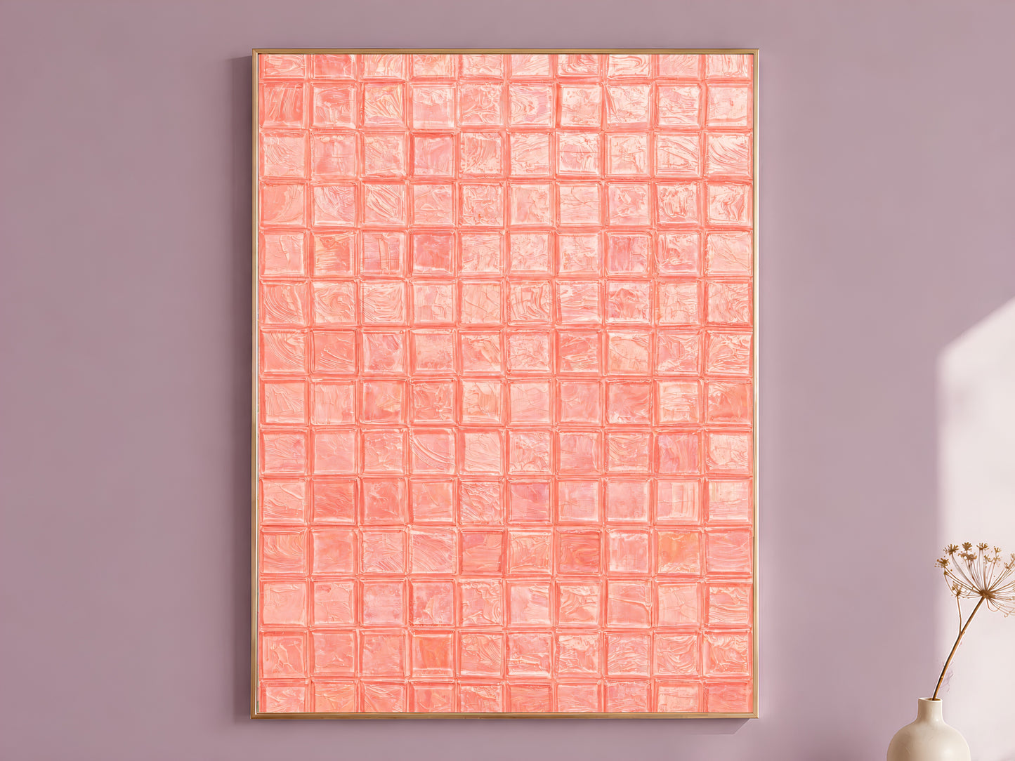 Salmon coral impasto mosaic tile wall art in a thin gold frame leaning against a dusty mauve wall with a dried allium stem in a cream vase beside it

