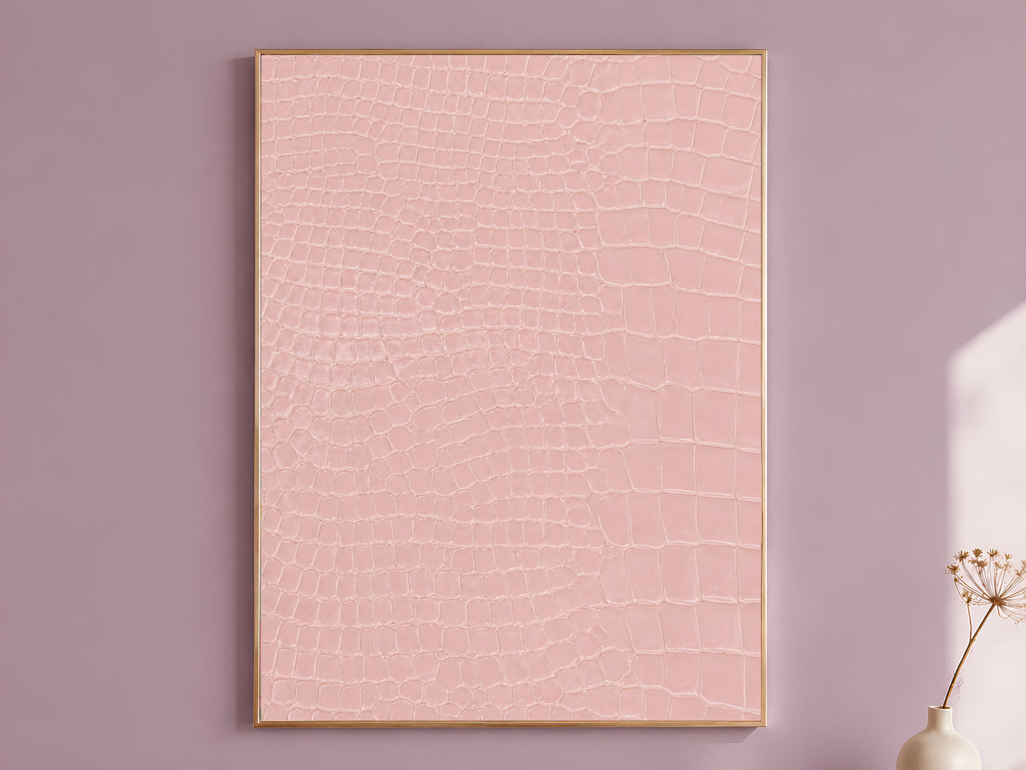 Pink crocodile print wall art in a gold frame hanging on a dusty mauve wall beside a vase of dried flowers.
