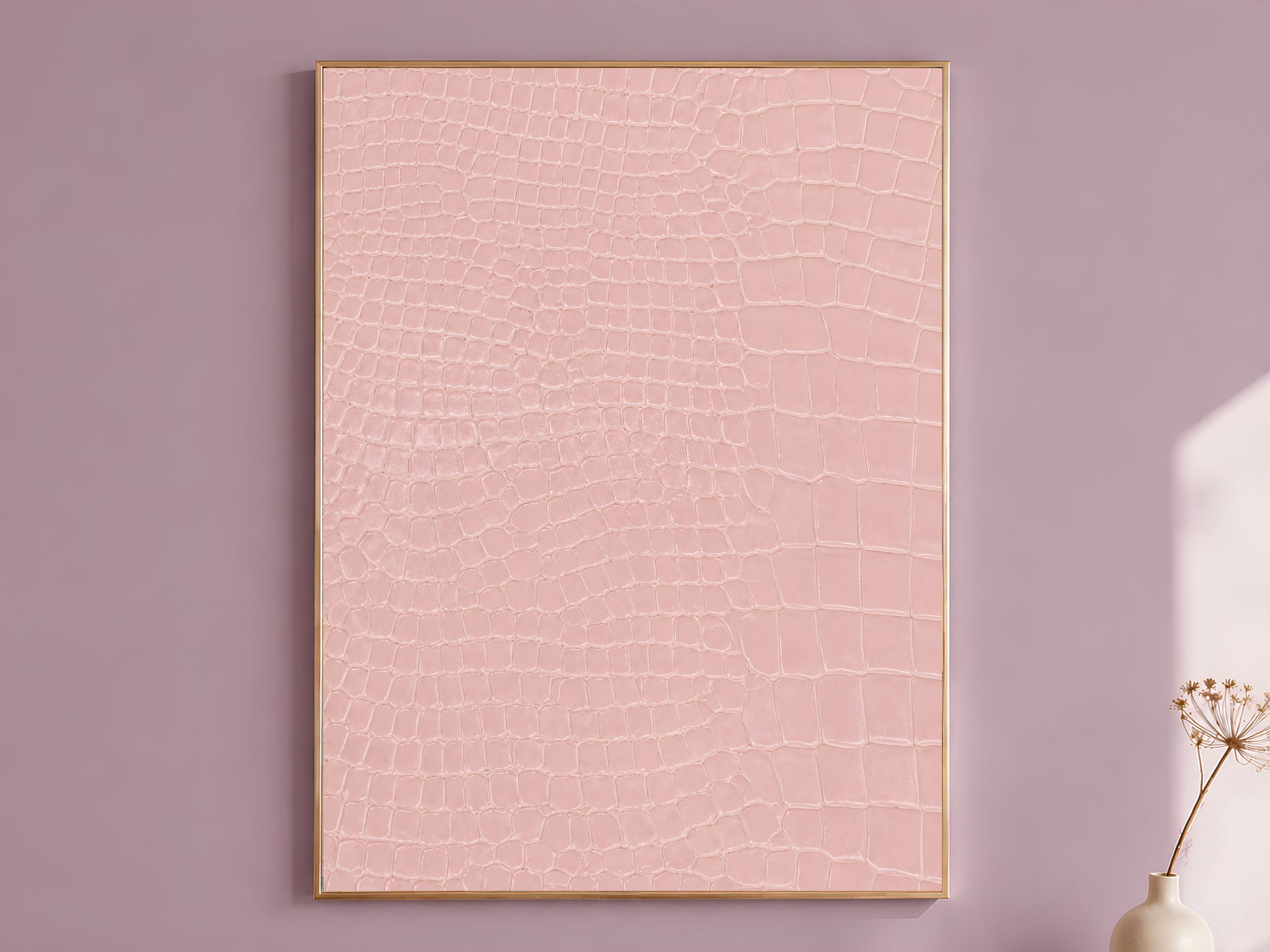 Pink crocodile print wall art in a gold frame hanging on a dusty mauve wall beside a vase of dried flowers.
