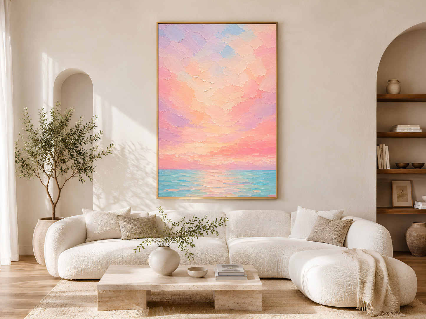 Pastel sunset ocean wall art print framed on a wall in an arched alcove living room with a cream boucle sectional sofa and wood coffee table.
