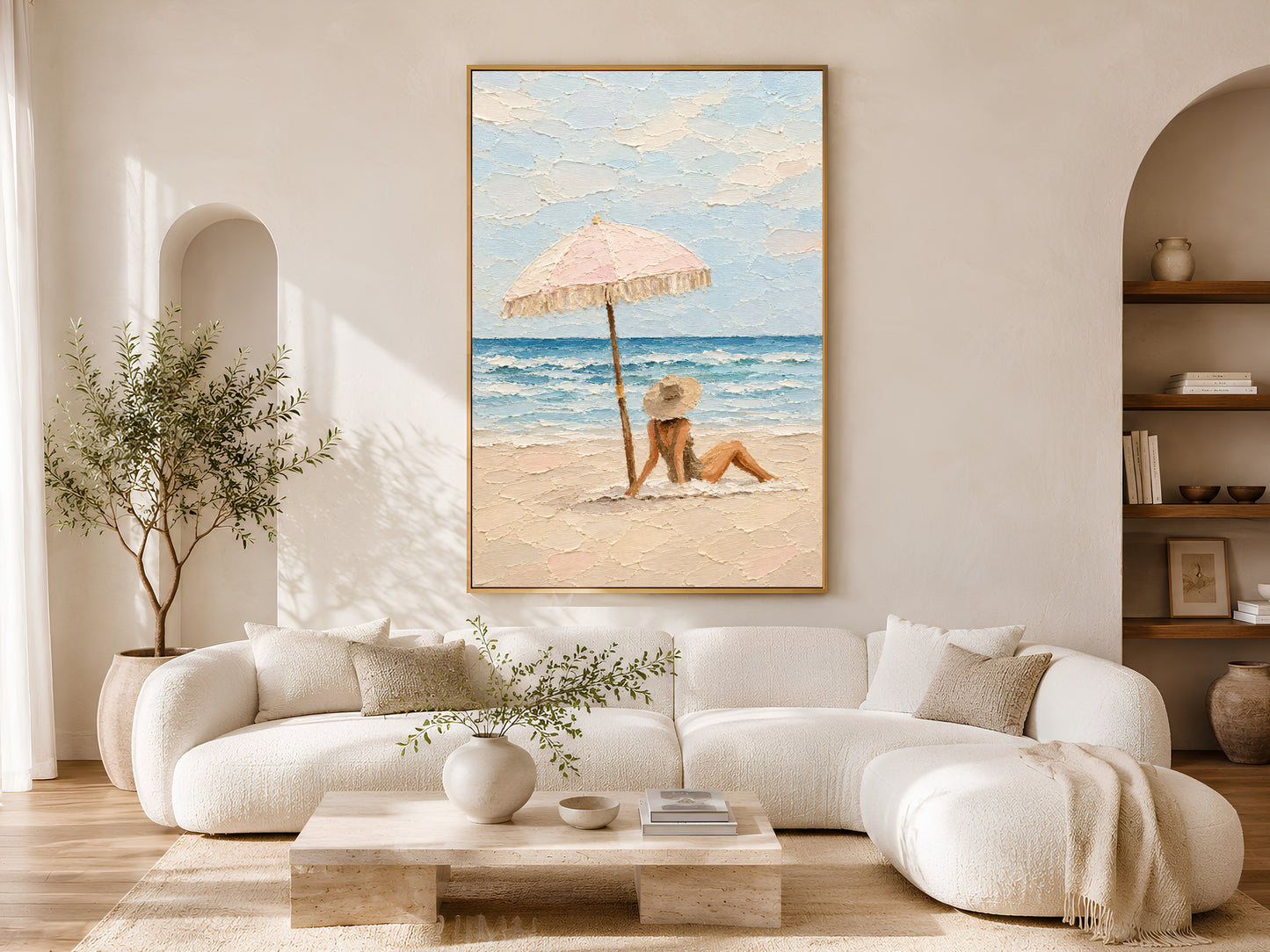 Framed beach scene impasto wall art displayed above a curved cream sofa in a bright boho living room with olive tree and arch detail
