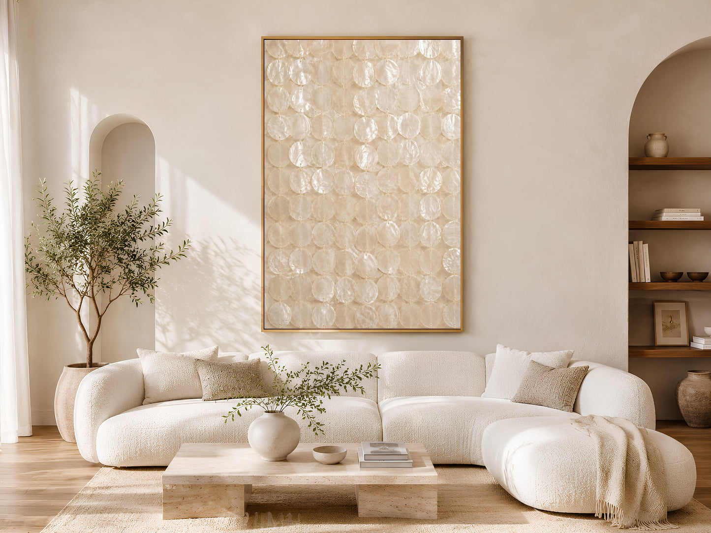 Capiz shell wall art print in a gold frame above a curved white sofa in a bright Scandinavian living room with warm wood coffee table, neutral cushions, and arched shelving
