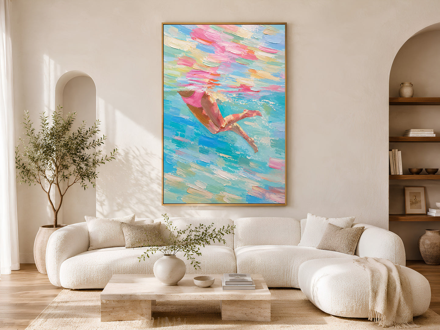 Woman swimmer diving impasto painting in a gold frame above a curved white sofa in a bright Scandinavian living room with warm wood coffee table and arched shelving
