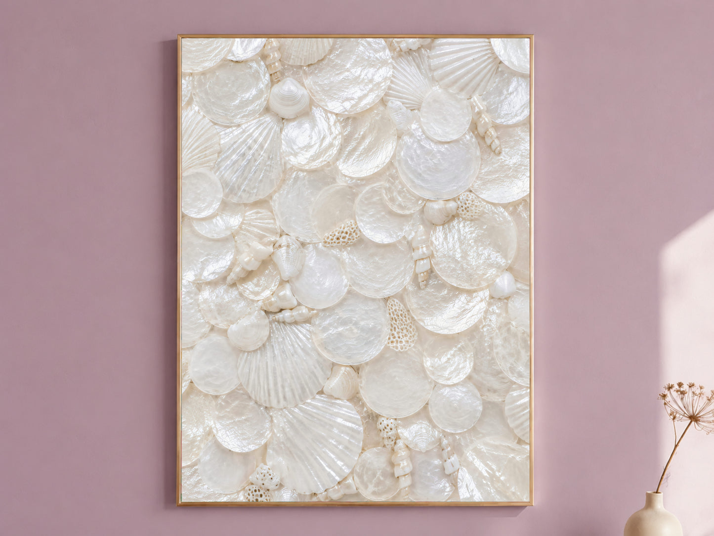 Mother of pearl wall art in a thin gold frame hanging on a dusty mauve wall, styled with a small dried flower vase.