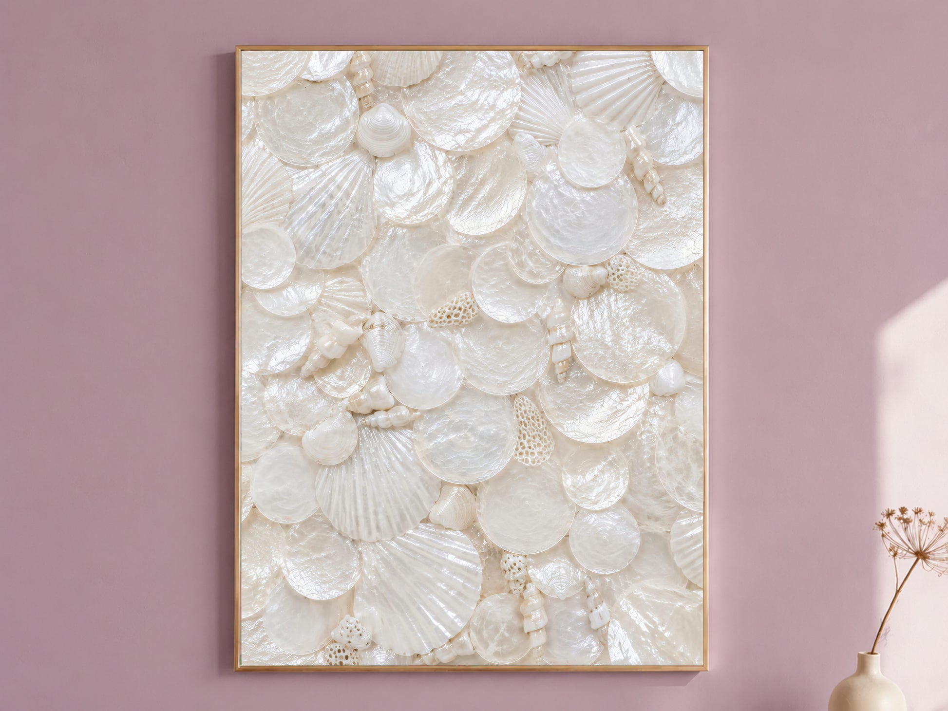 Mother of pearl wall art in a thin gold frame hanging on a dusty mauve wall, styled with a small dried flower vase.