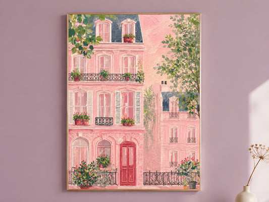 Impasto oil painting pink Parisian building wall art in a thin gold frame leaning against a dusty mauve wall with a dried allium stem in a cream vase beside it
