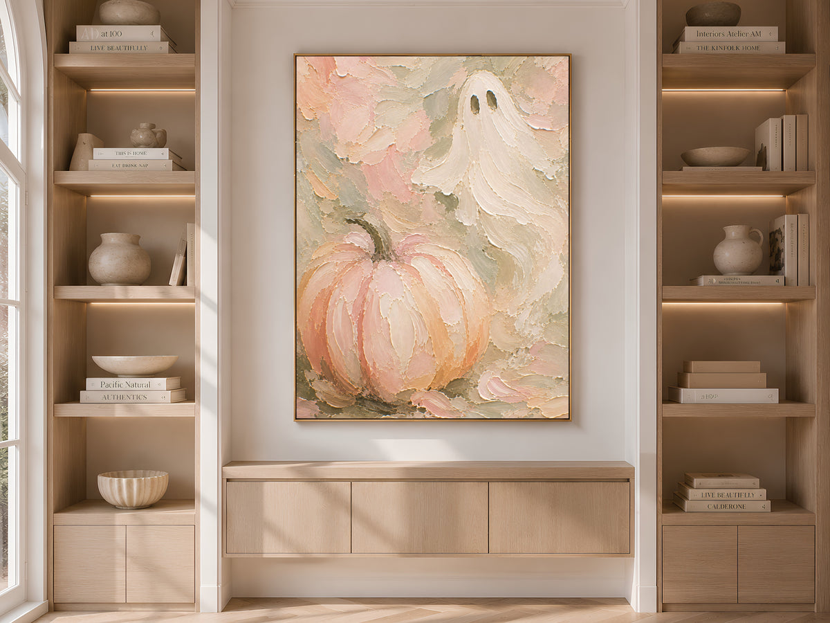 Pastel Halloween pumpkin wall art print displayed above a built-in cabinet between wooden bookshelves