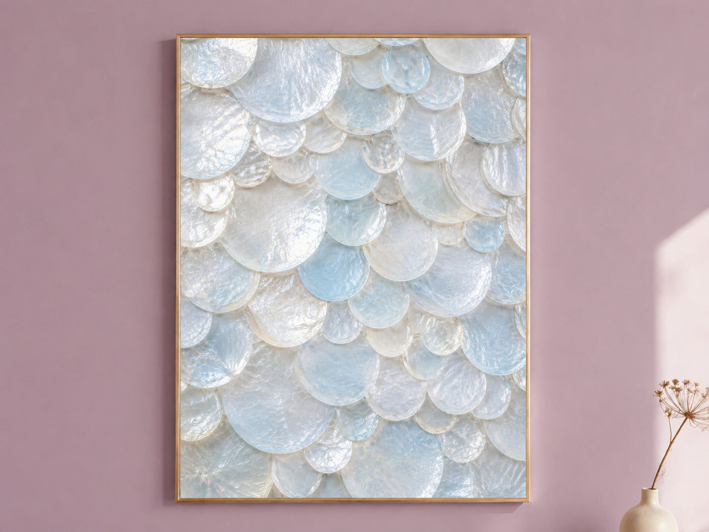 Sea glass wall art in a thin gold frame hanging on a dusty mauve wall, styled with a small dried flower vase.