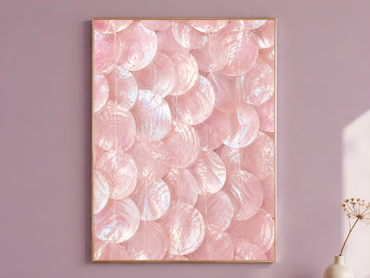 Pink capiz shell wall art print in a gold frame hanging on a dusty mauve wall beside a vase of dried flowers.
