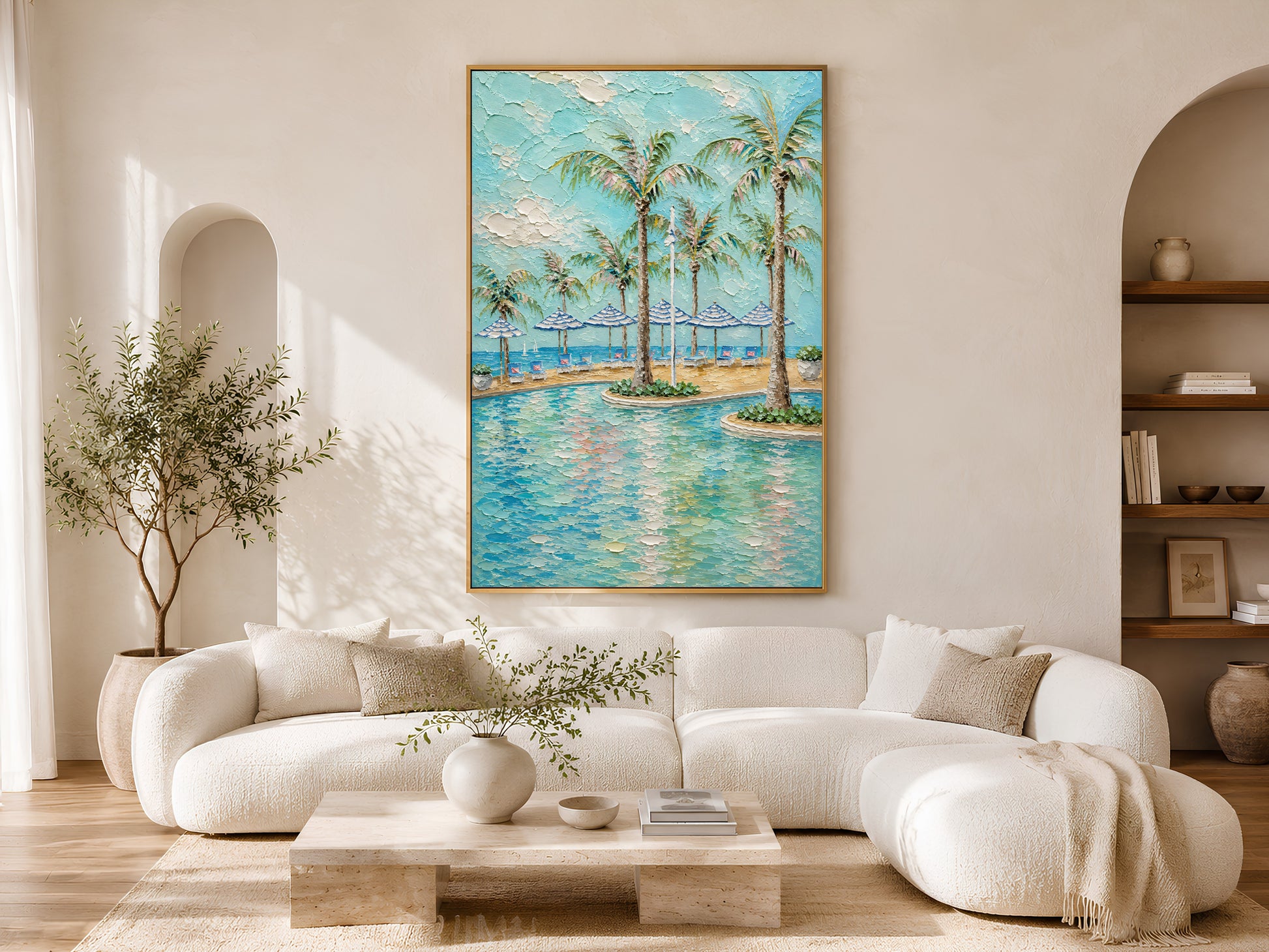 Gold-framed palm tree resort pool wall art above a cream curved sofa in a bright minimalist living room with arched wall detail, olive tree, and low round coffee table
