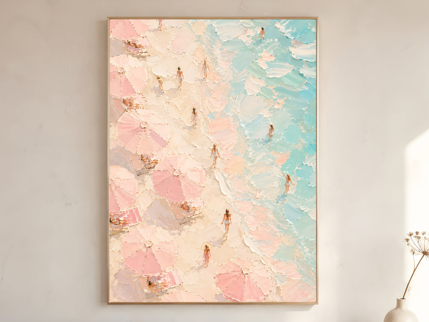 Aerial beach impasto wall art print in blush pink, cream and teal in a gold frame leaning against a warm white wall with dried floral stems
