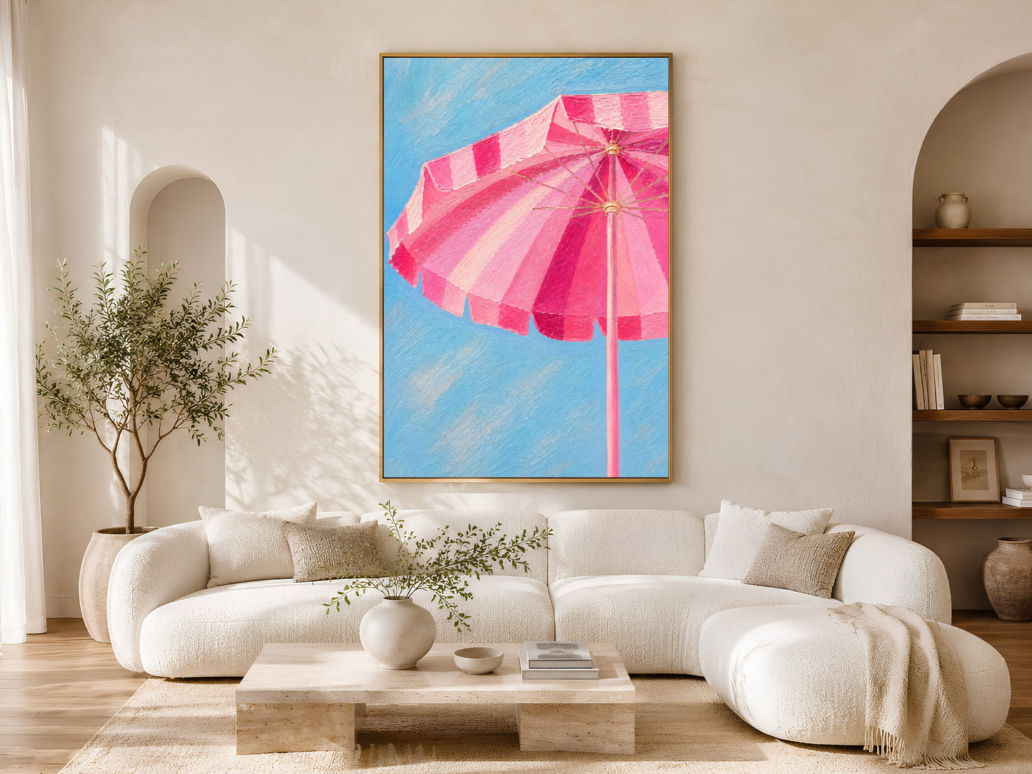Pink beach umbrella wall art printable displayed above a curved cream sofa in a luxury coastal living room with warm neutral styling.