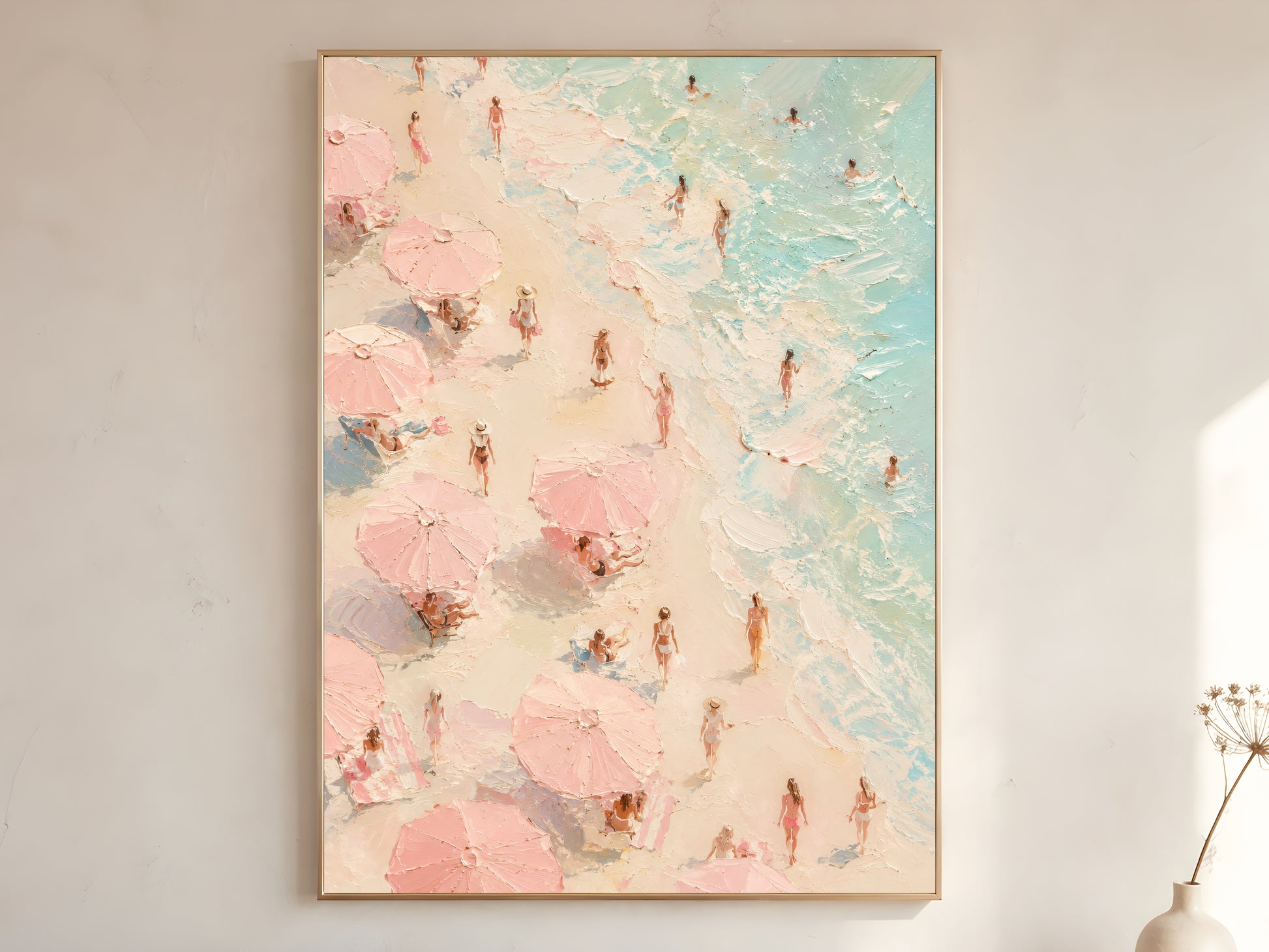 Aerial pink beach scene oil painting in gold frame leaning against a white wall with dried florals